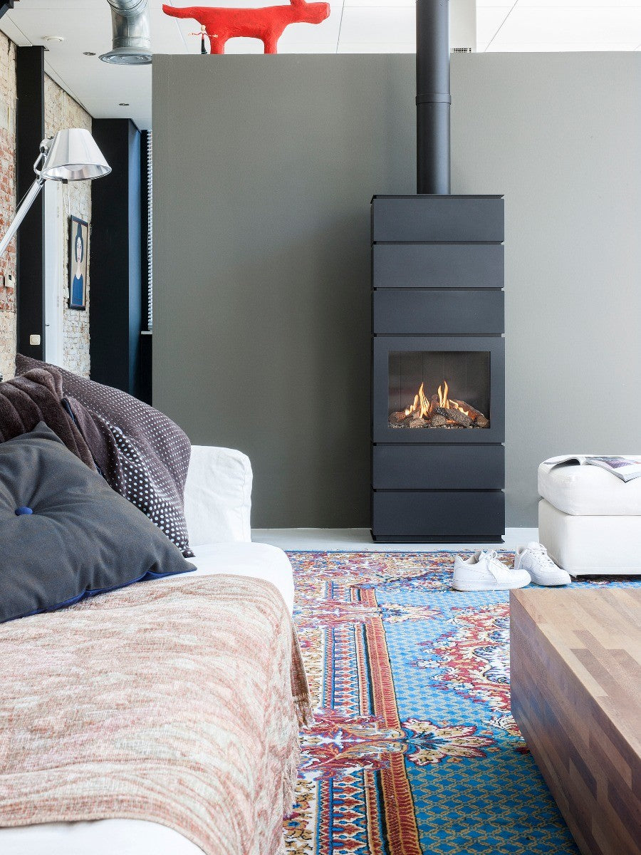 Faber Blokhus haard in een moderne woonkamer met kleurrijk tapijt en comfortabele meubels.