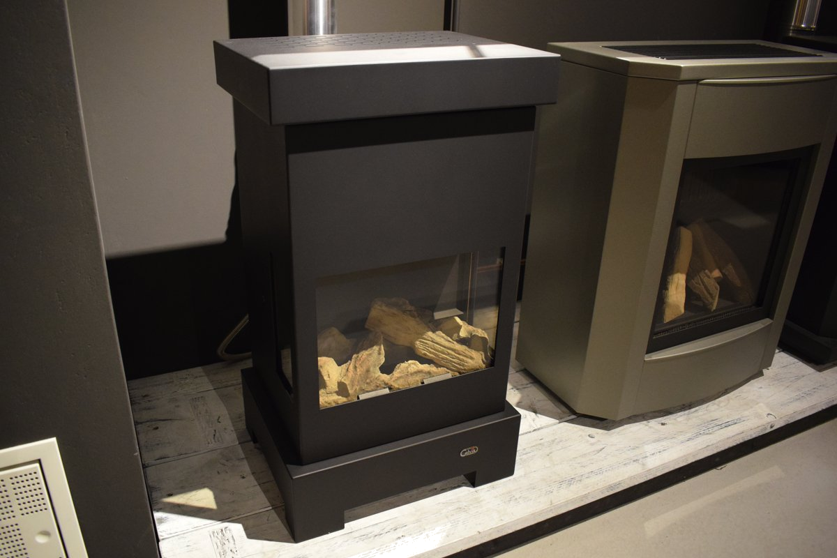 Calvix Sparky zwarte kachel met glazen deur en houtblokken, showroomopstelling