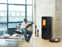Jydepejsen Cozy Modern in woonkamer naast man met boek en brandend vuur