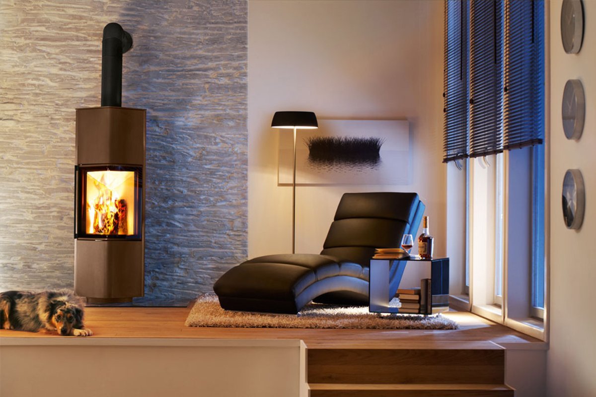 Spartherm Cubo L hangende houtkachel in woonkamer, brandend bij fauteuil