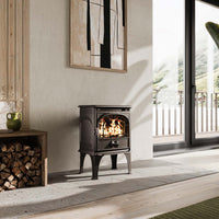 Dovre 250CBS-houtkachel brandend in een lichte woonkamer naast een houtopslag