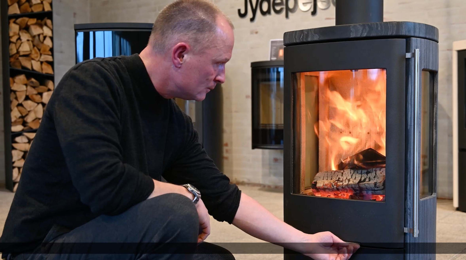 Jydepejsen Senza in showroom, met brandend hout en een man ernaast