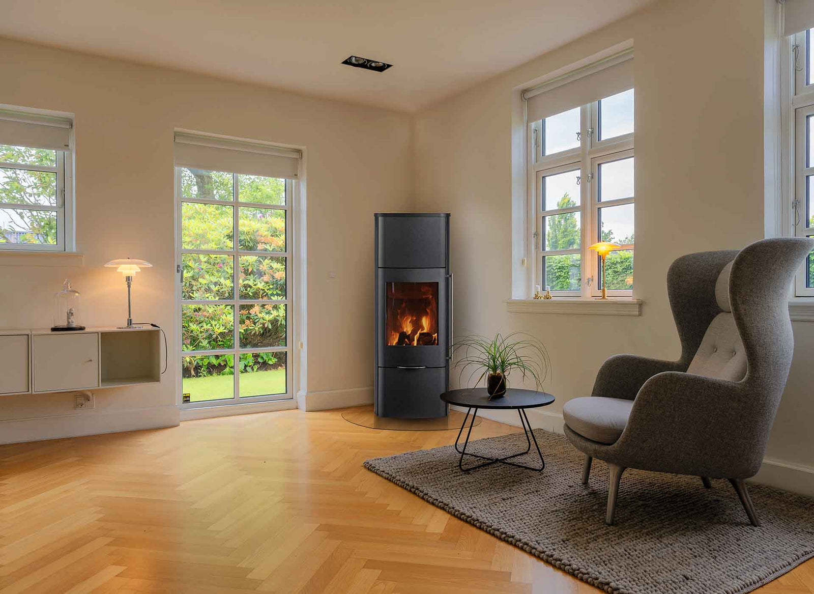 Jydepejsen Senza High kachel in woonkamer met brandend vuur en fauteuil