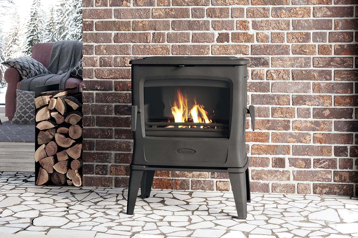 Dovre TAI45WD houtkachel met brandend vuur voor bakstenen muur