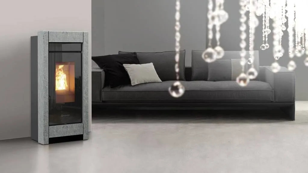 Thermorossi Essenza Metalcolor Natural Air pelletkachel naast een grijze bank in een moderne woonkamer.